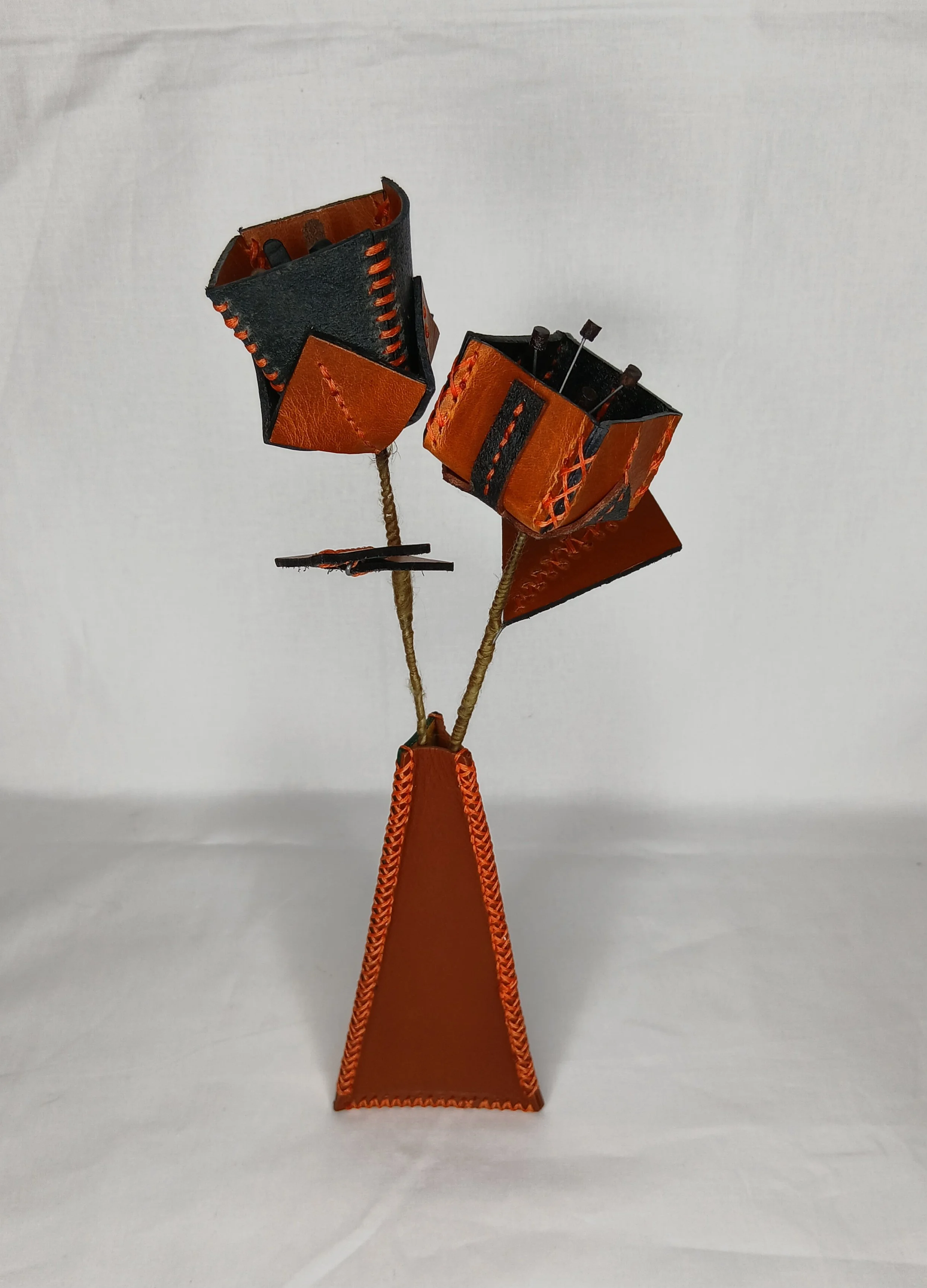 𝗖𝘂𝗯𝗶𝘀𝘁 𝗶𝗻 𝗕𝗹𝗼𝗼𝗺 — A striking contemporary sculpture featuring sharply structured, contrasting black and orange geometric forms held with intricate hand-stitched detailing and cross-weave edging.