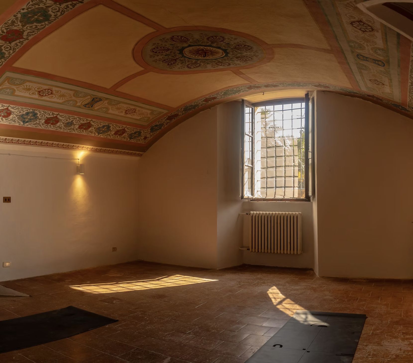 Four women participating in a Pilates or barre class using reformer machines and holding rings in a bright studio with mirrors.