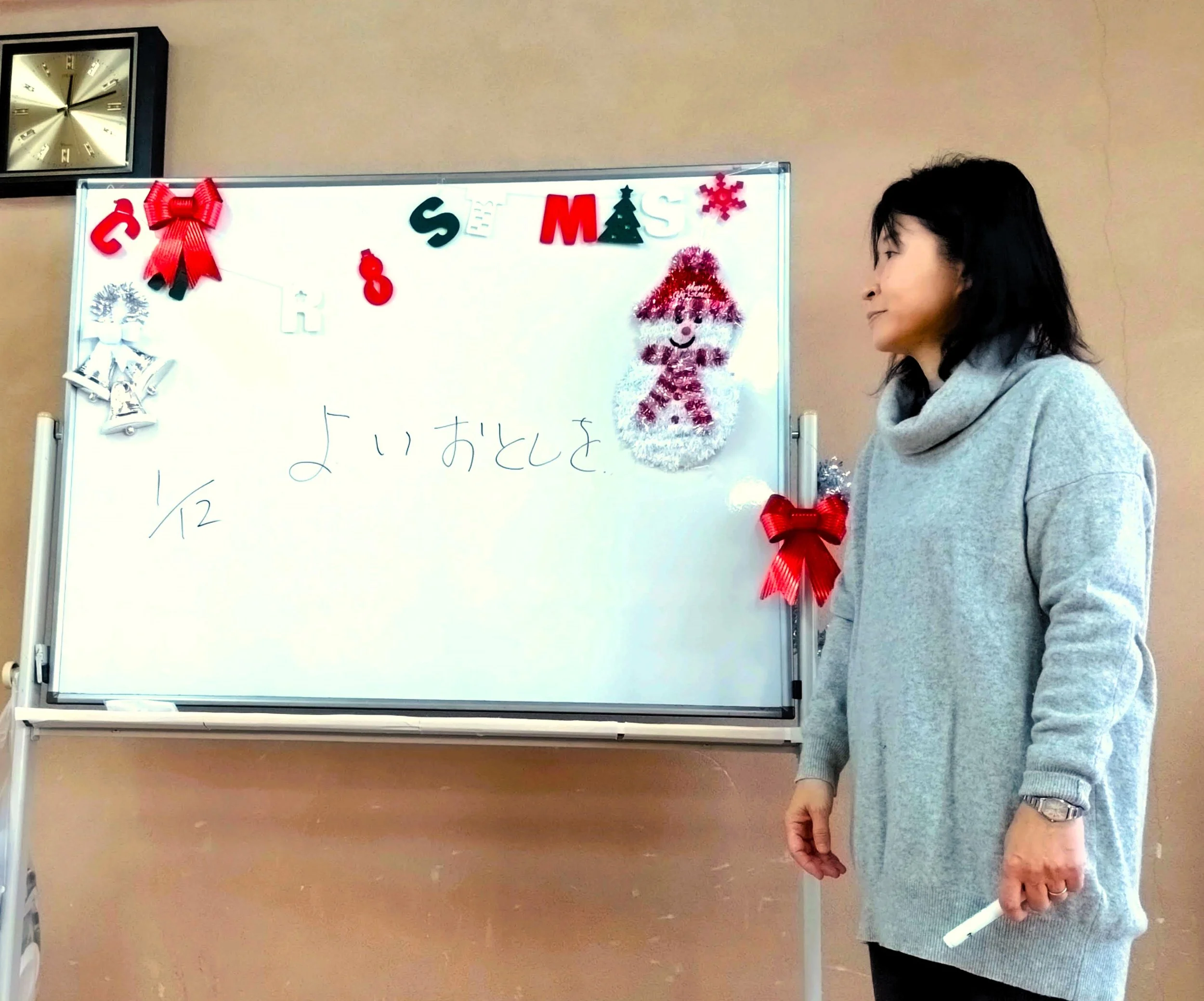 日本語での年末の挨拶をホワイトボードに書いて説明する先生