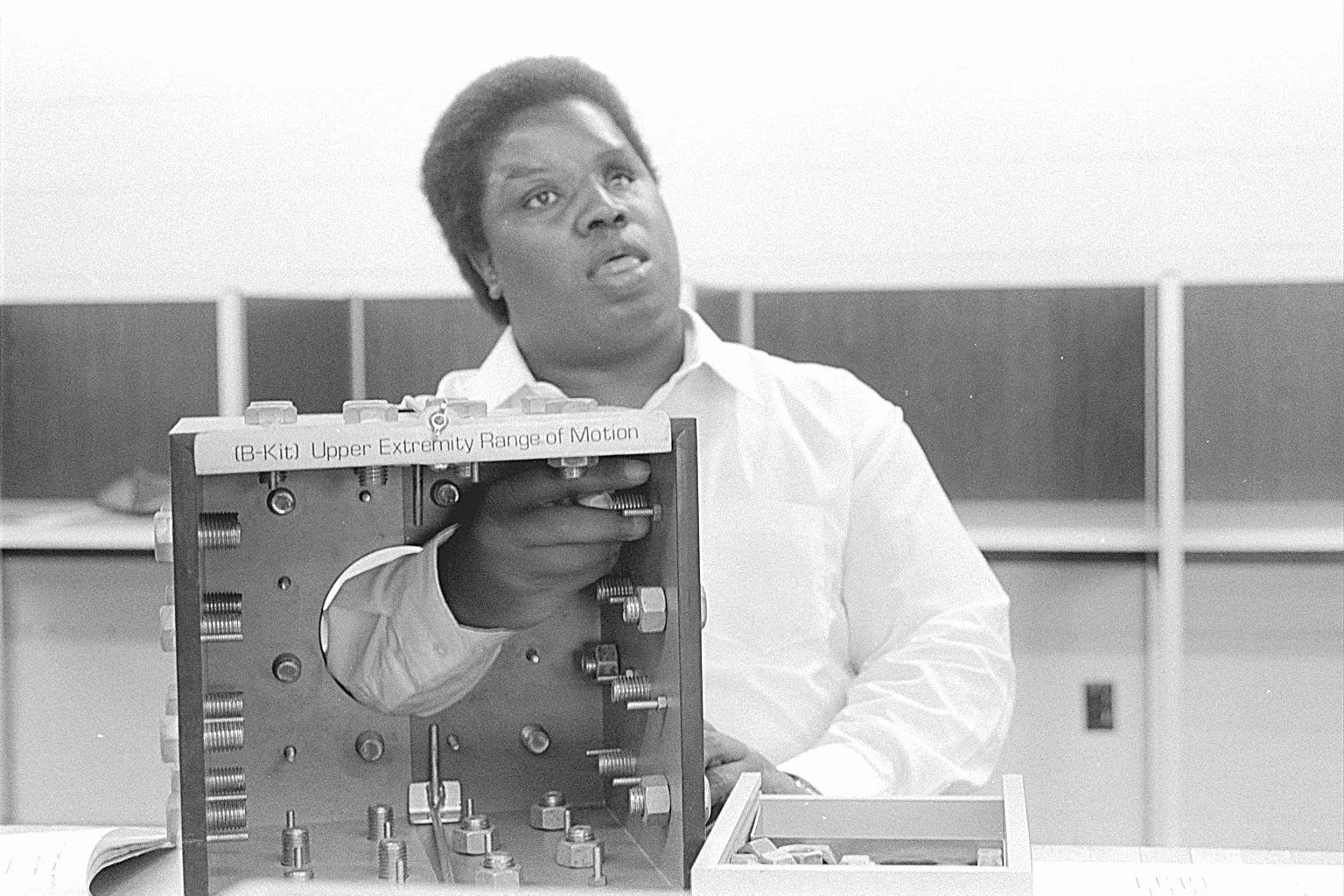 Person examining a device labeled 'B-Kit Upper Extremity Range of Motion' in a laboratory.