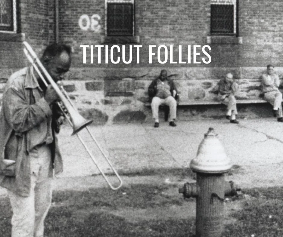 Black and white photo of a man playing a trombone in front of a brick building with "Titicut Follies" text.