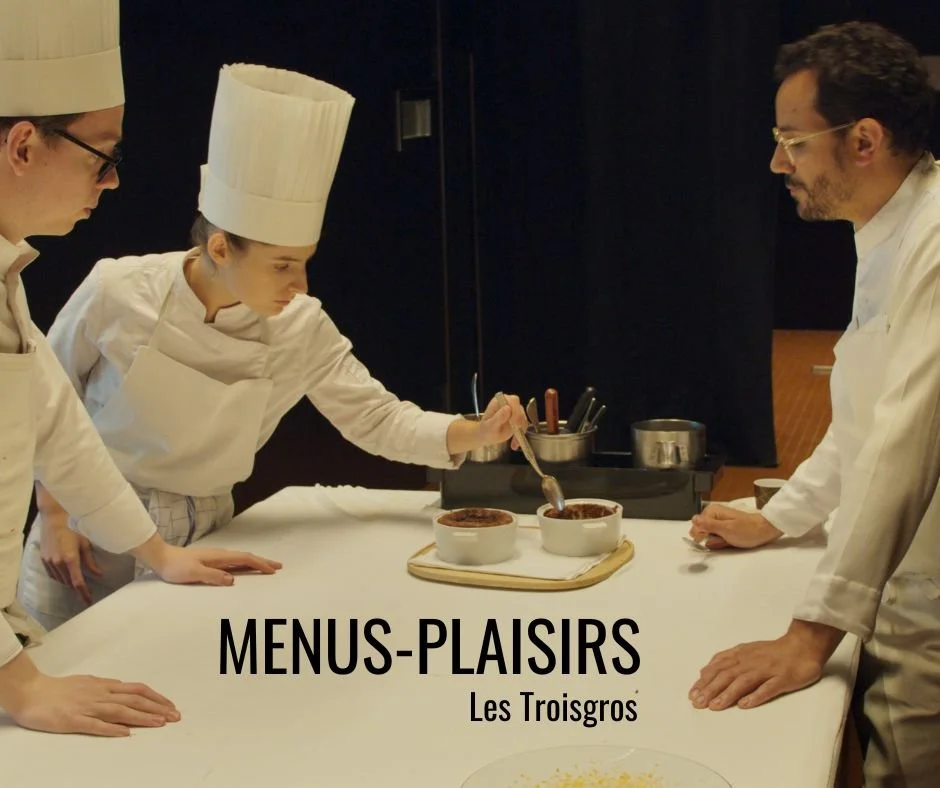 Chefs preparing dishes in a kitchen labeled 'Menus-Plaisirs Les Troisgros'