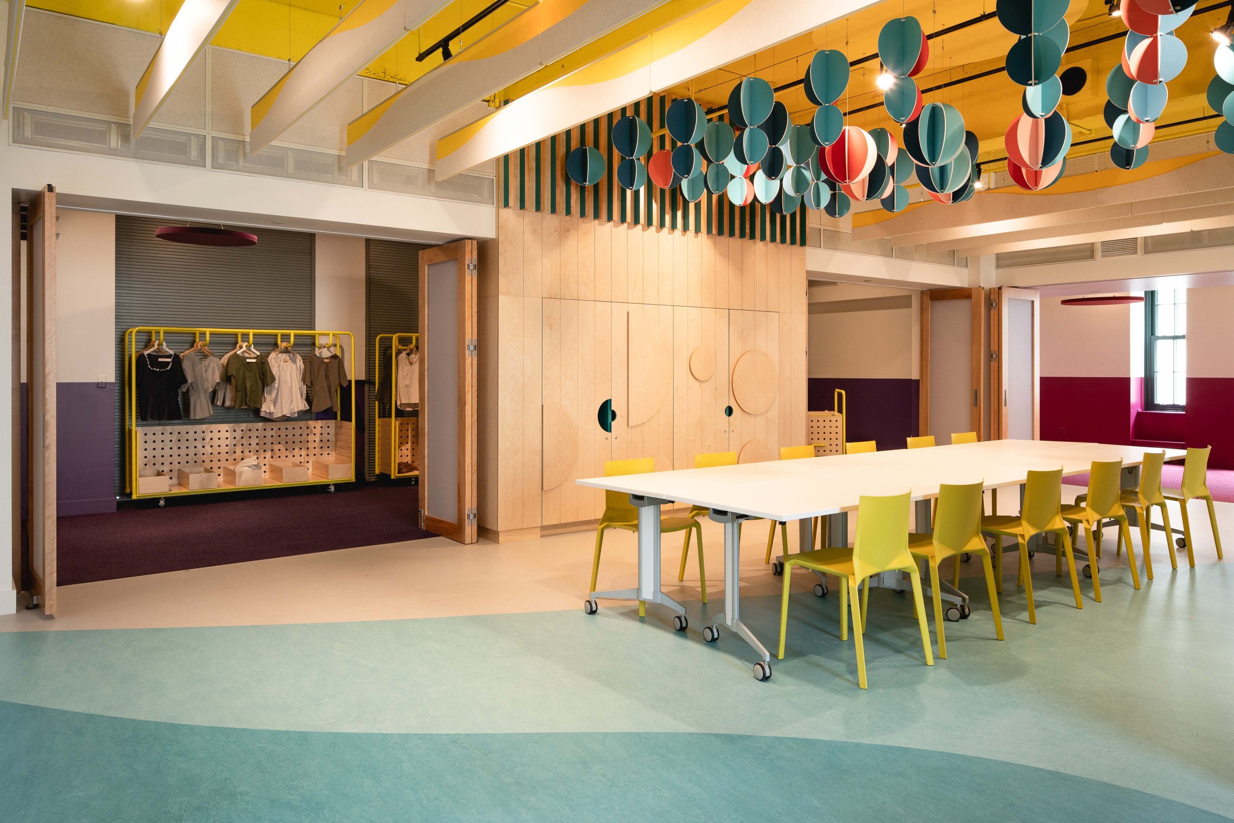 Design de l'espace centrale donnant sur les trois salles d'activités séparée par des portes de bois pliantes par inscape