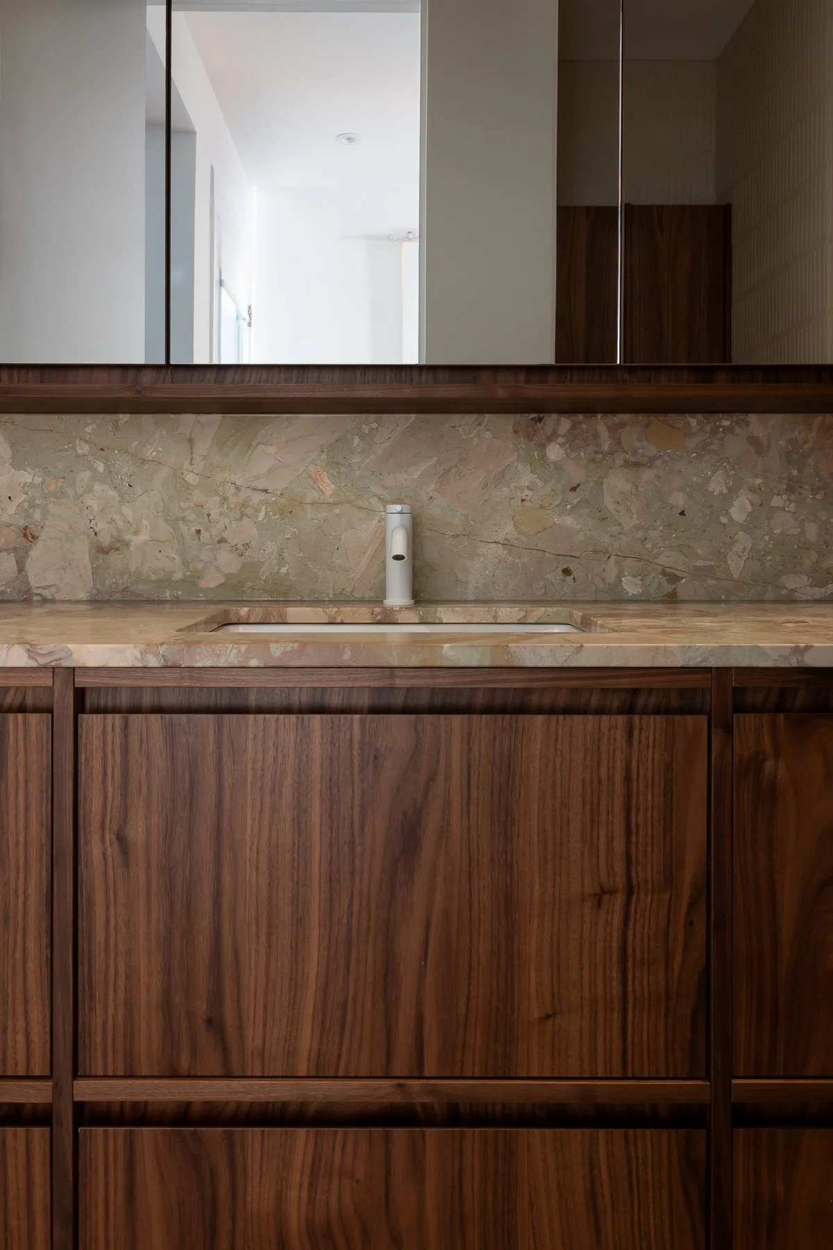 Design du comptoir de pierre avec des couleurs riches de beige, rosé et vert s'harmonisant à la chaleur du noyer par inscape le studio