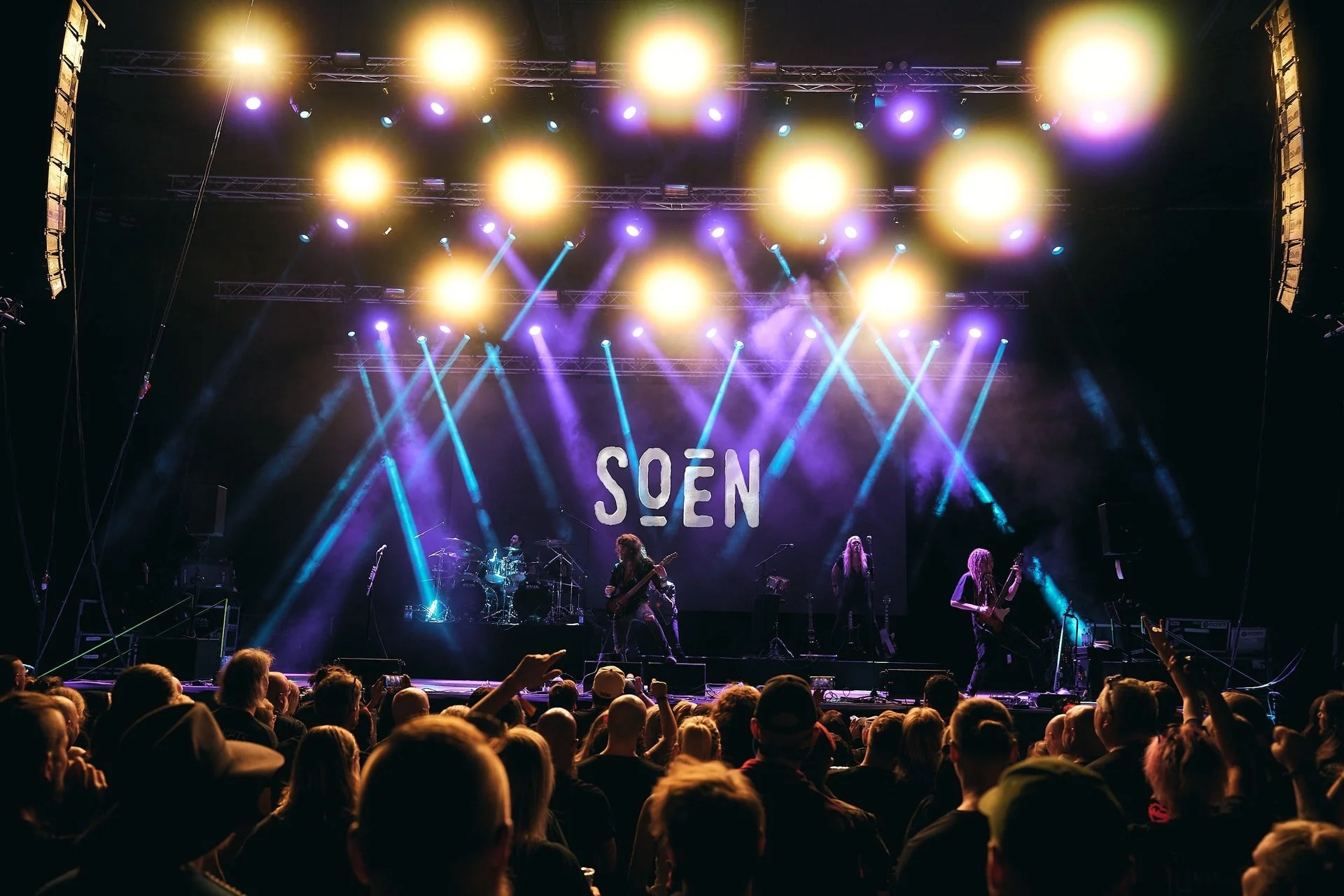 Bändi esiintyy lavalla konsertissa, valot loistavat värikkäästi.