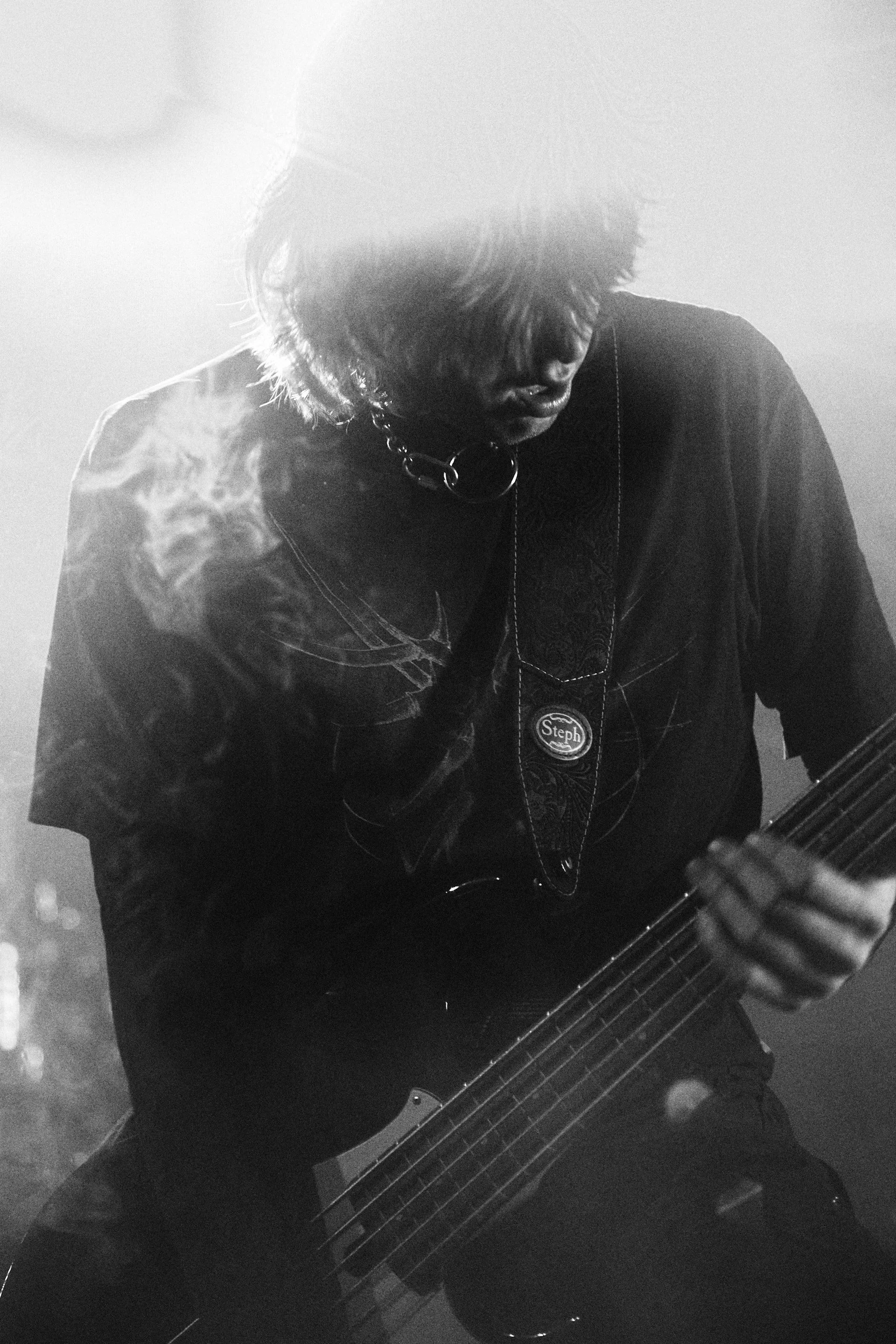 Mies soittaa kitaraa savuisessa valaistuksessa.