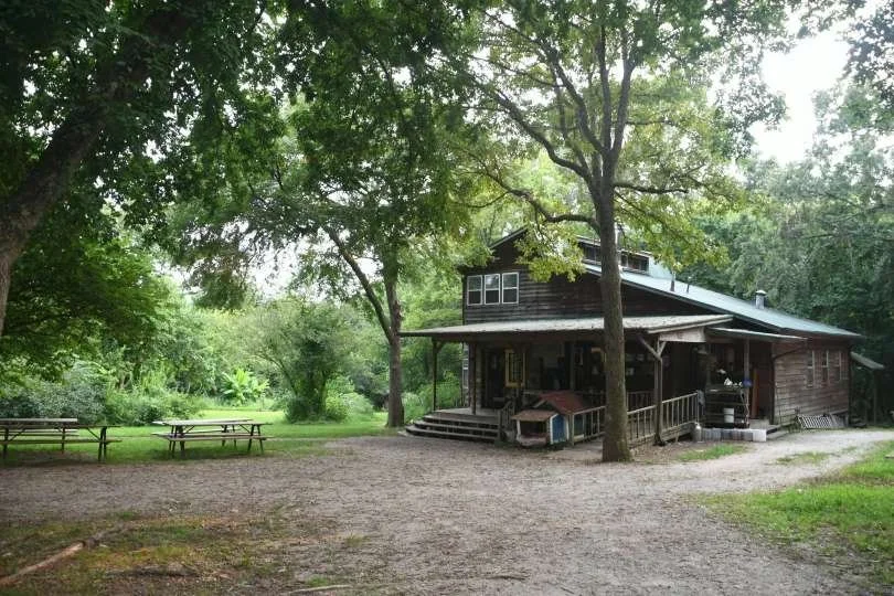 Photograph of a rustic-looking wooden building surrounded by lush trees and woods at East Wind Community