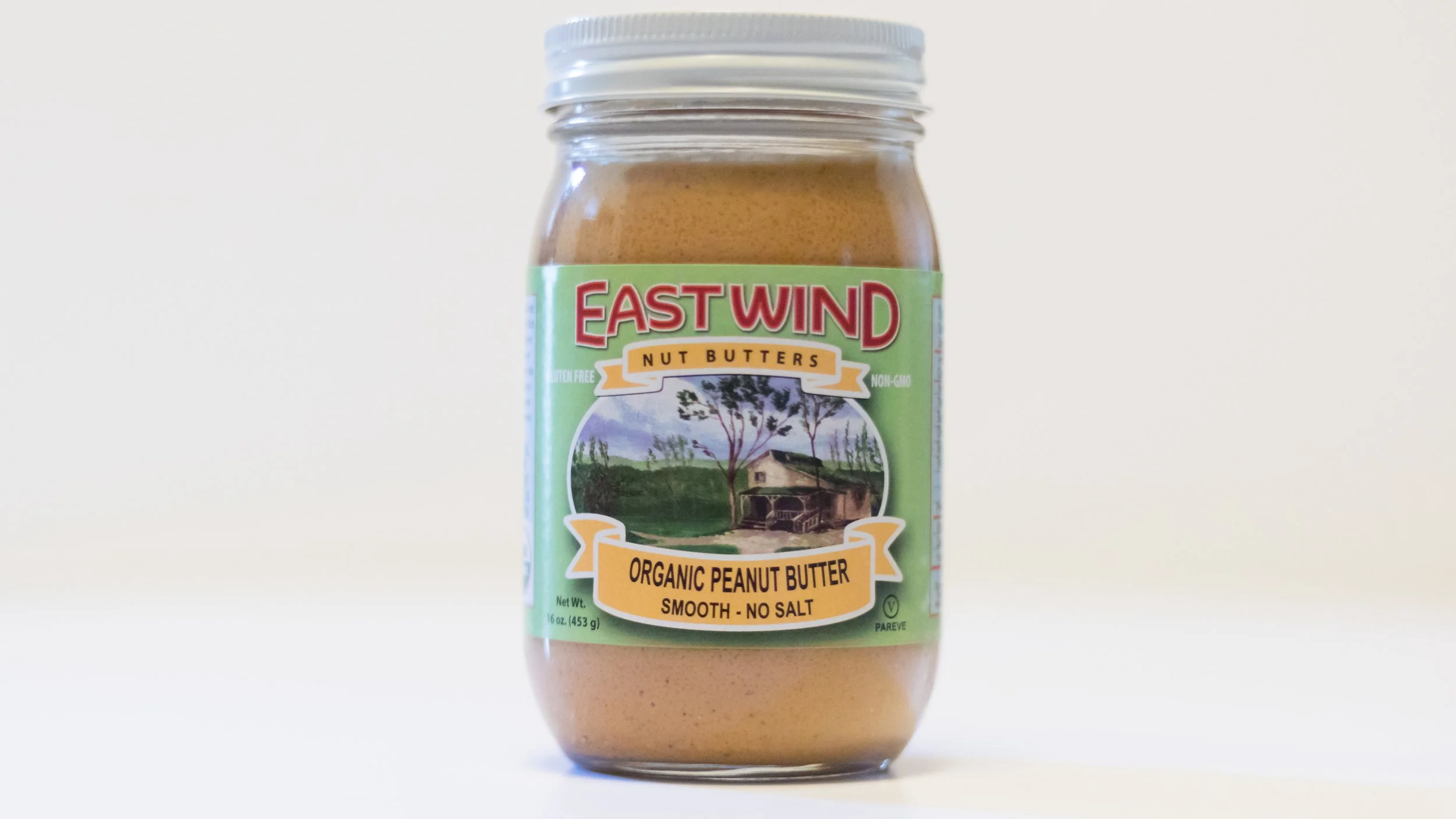 a glass jar of 16 oz. smooth, no salt east wind organic valencia peanut butter