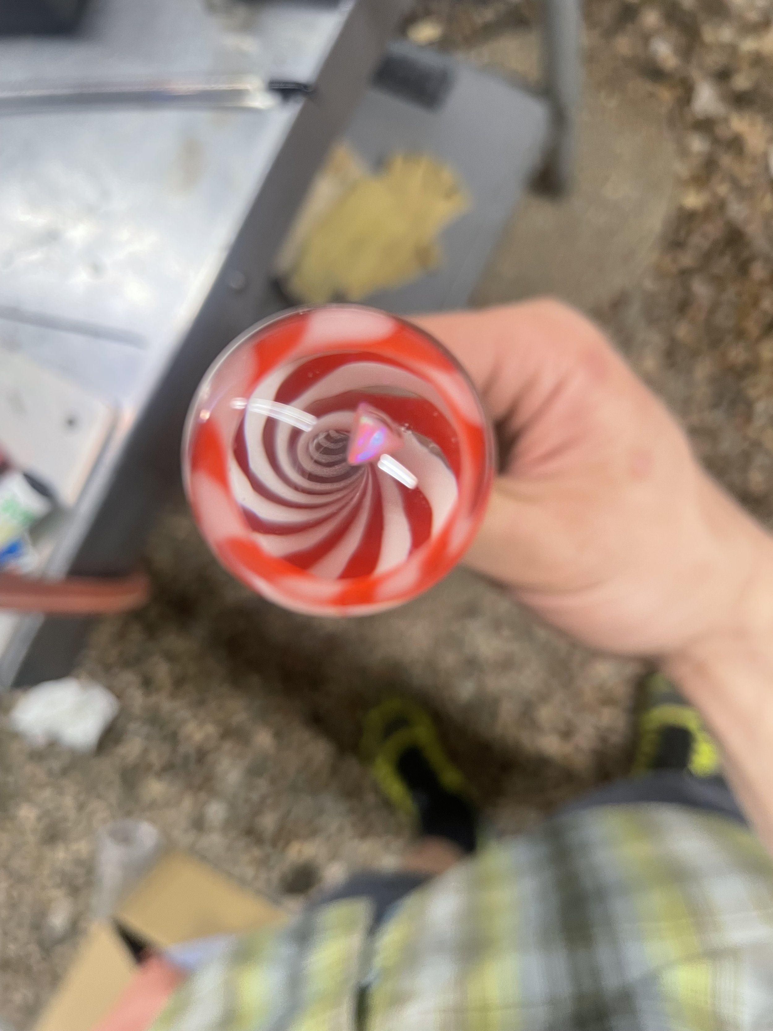 Top view of a hand holding a glass with red and white swirled candy cane pattern inside.
