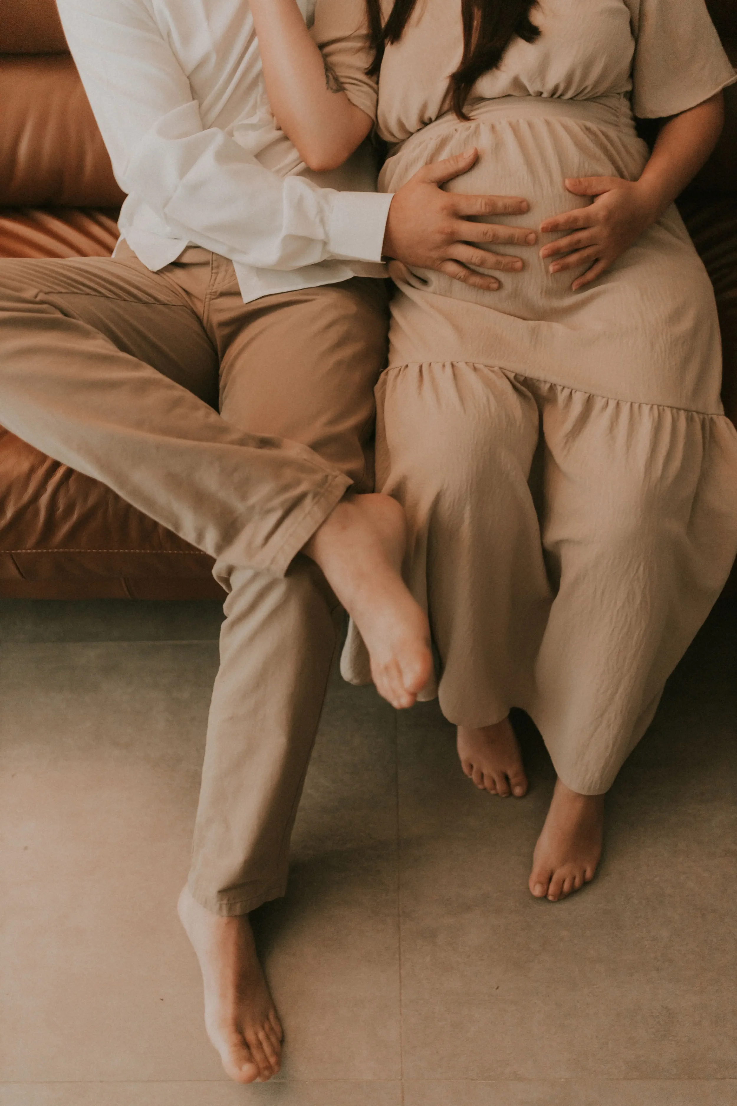 Expecting couple sitting together with hands on a baby bump, symbolizing teamwork and preparation for becoming parents.