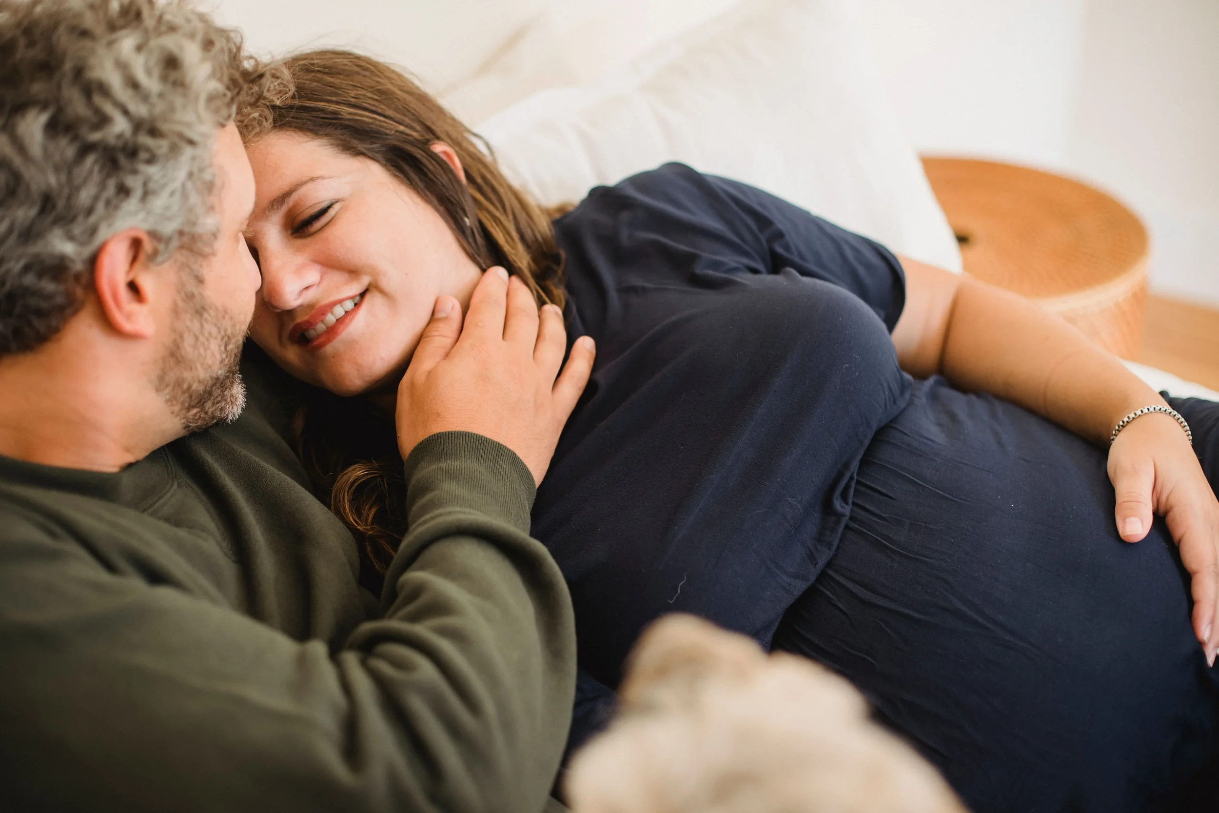 Expecting couple cuddling on a couch as they prepare for parenthood and work on staying connected through life's transitions.