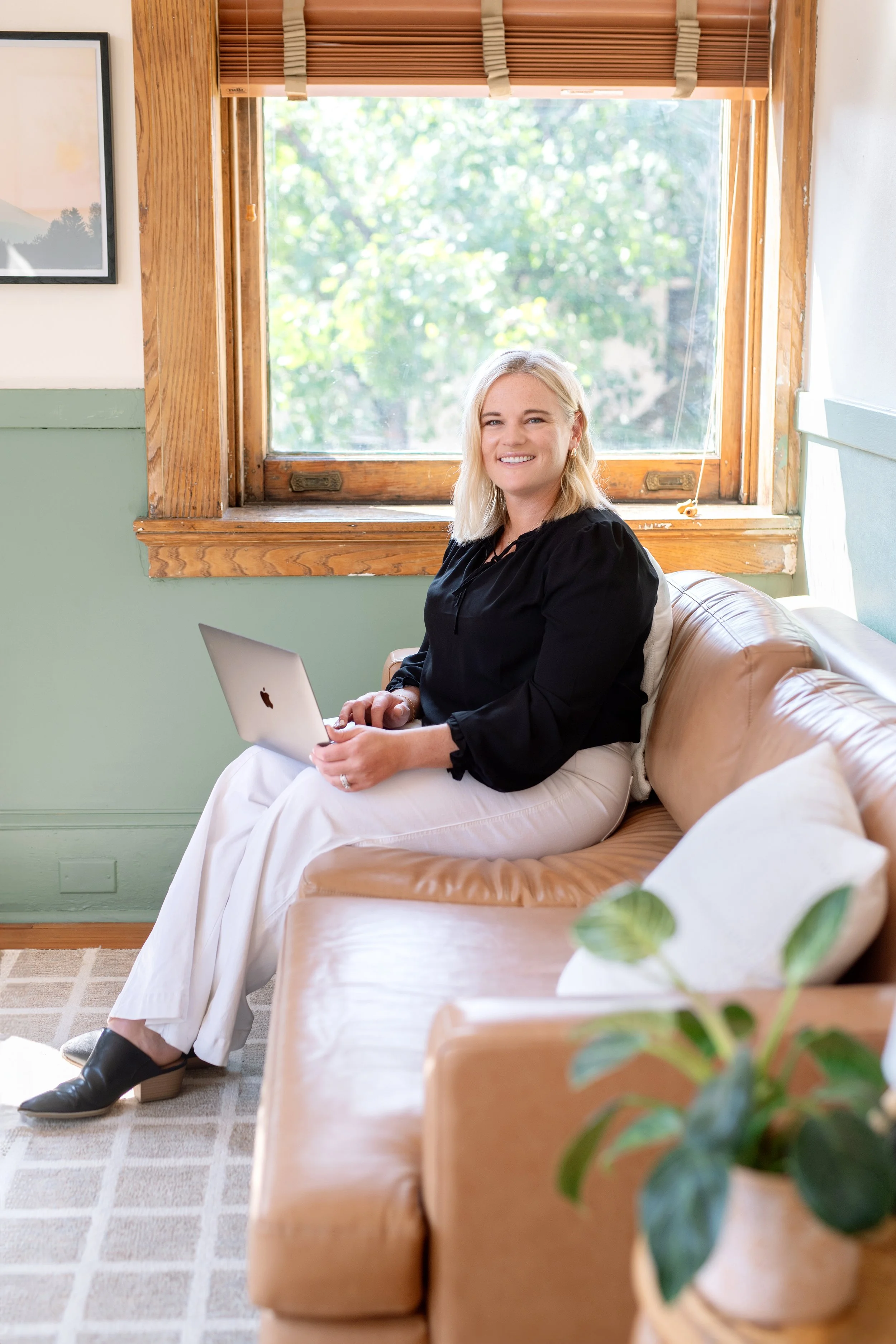 Therapist sitting in her office with computer in her lap ready to start a therapy session with a mom in Maryland