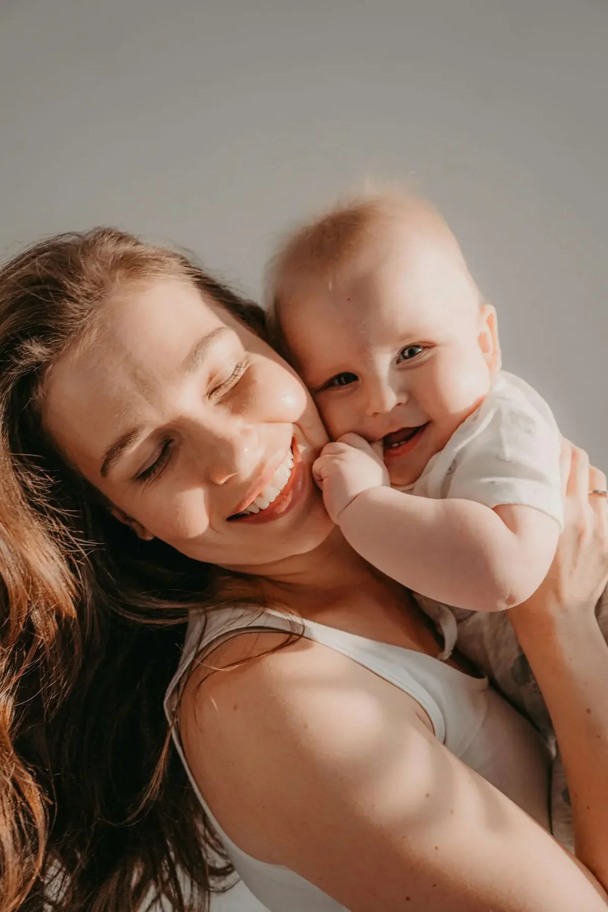 Mother smiling while holding her baby, representing connection and resilience in motherhood