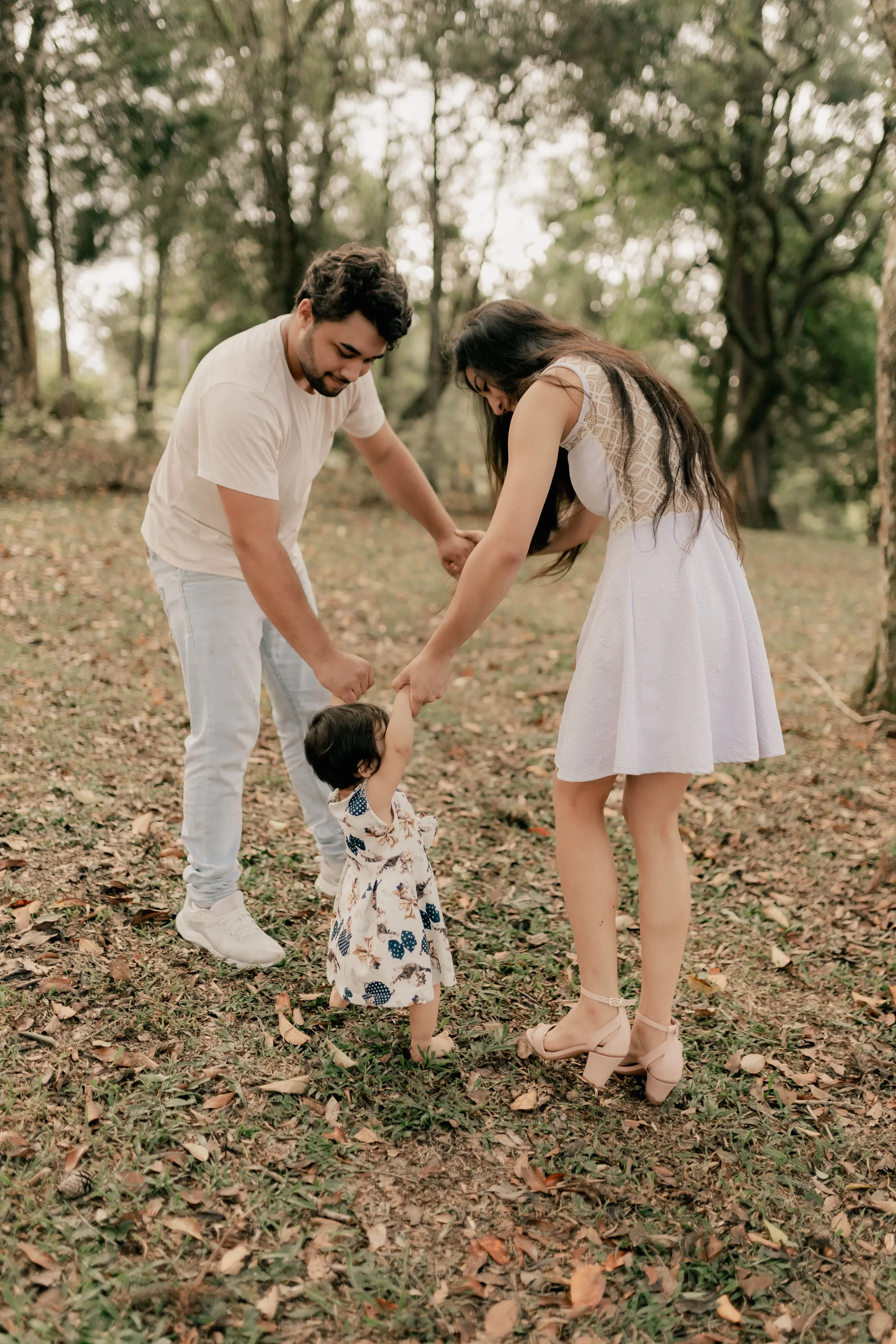 Parents helping their young child take steps together, representing teamwork and building a strong family foundation.