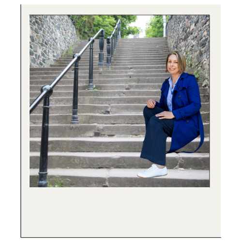 Polaroid of Jane Feilden sitting on steps outside.