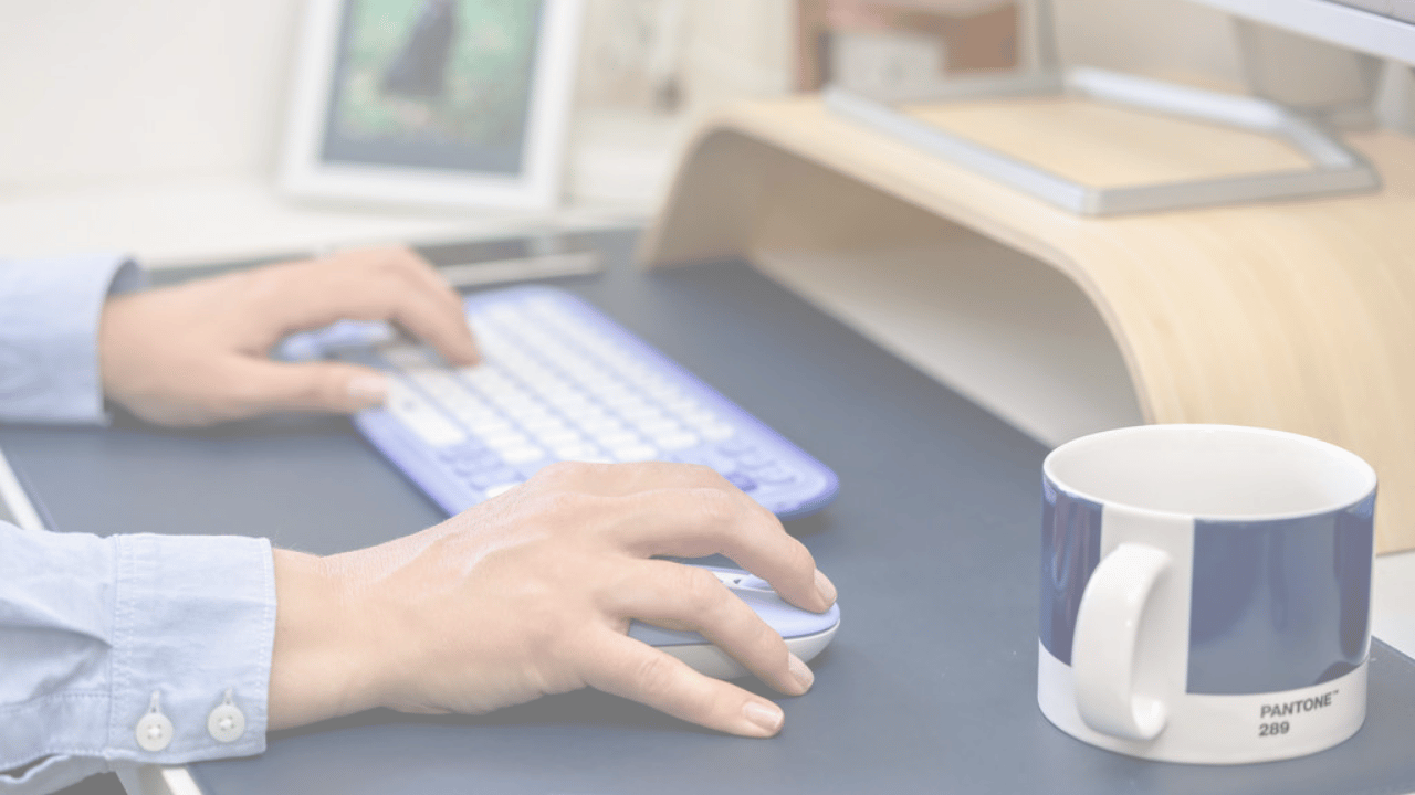 Close up of two hands working on a laptop and operating a mouse.