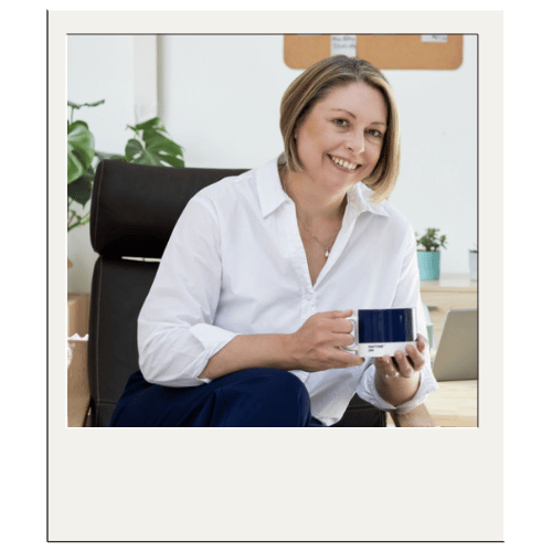 Polaroid of Jane Feilden sitting in a chair holding a cup of coffee.