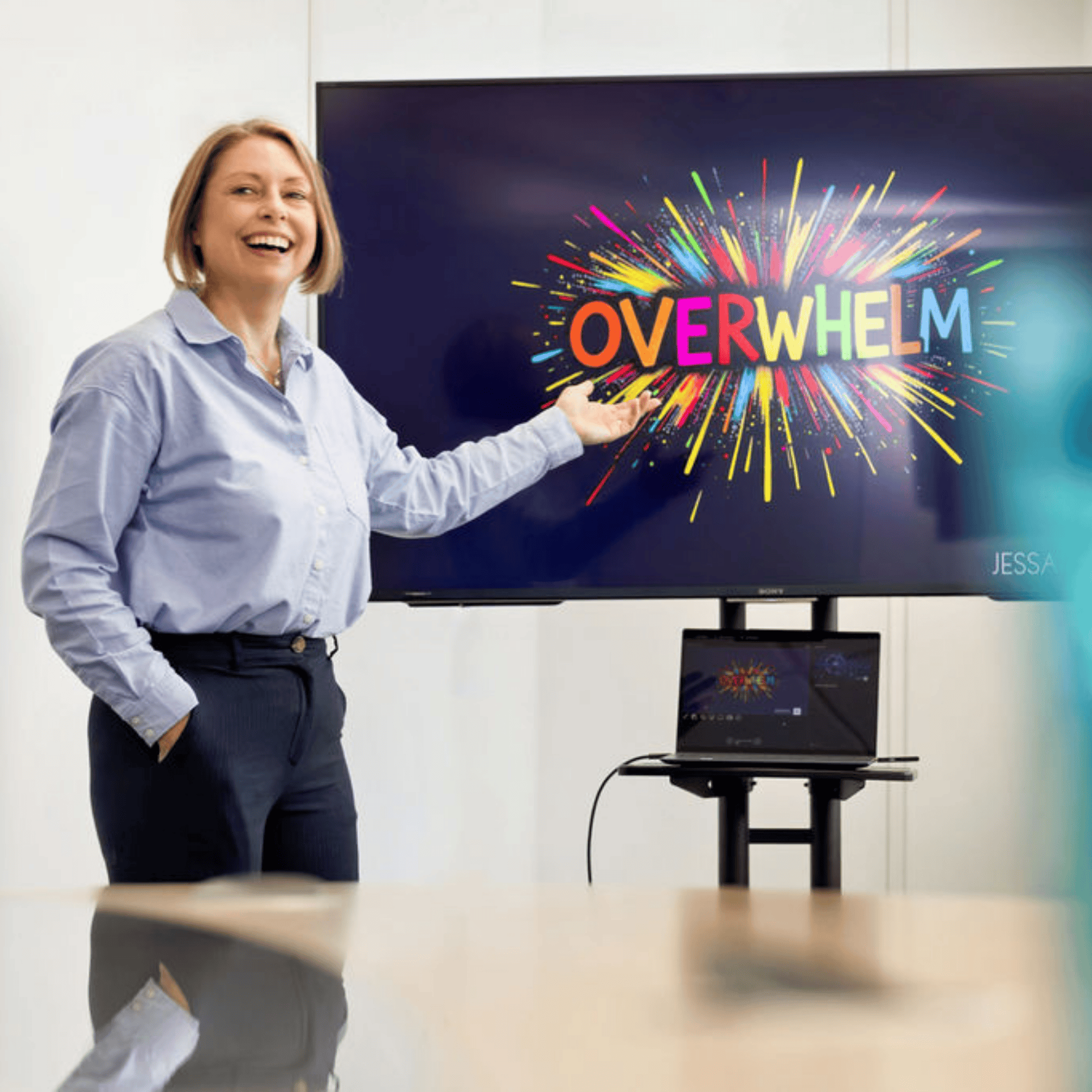 Jane Feilden presenting in front of a large screen. The word overwhelm is written on the screen.