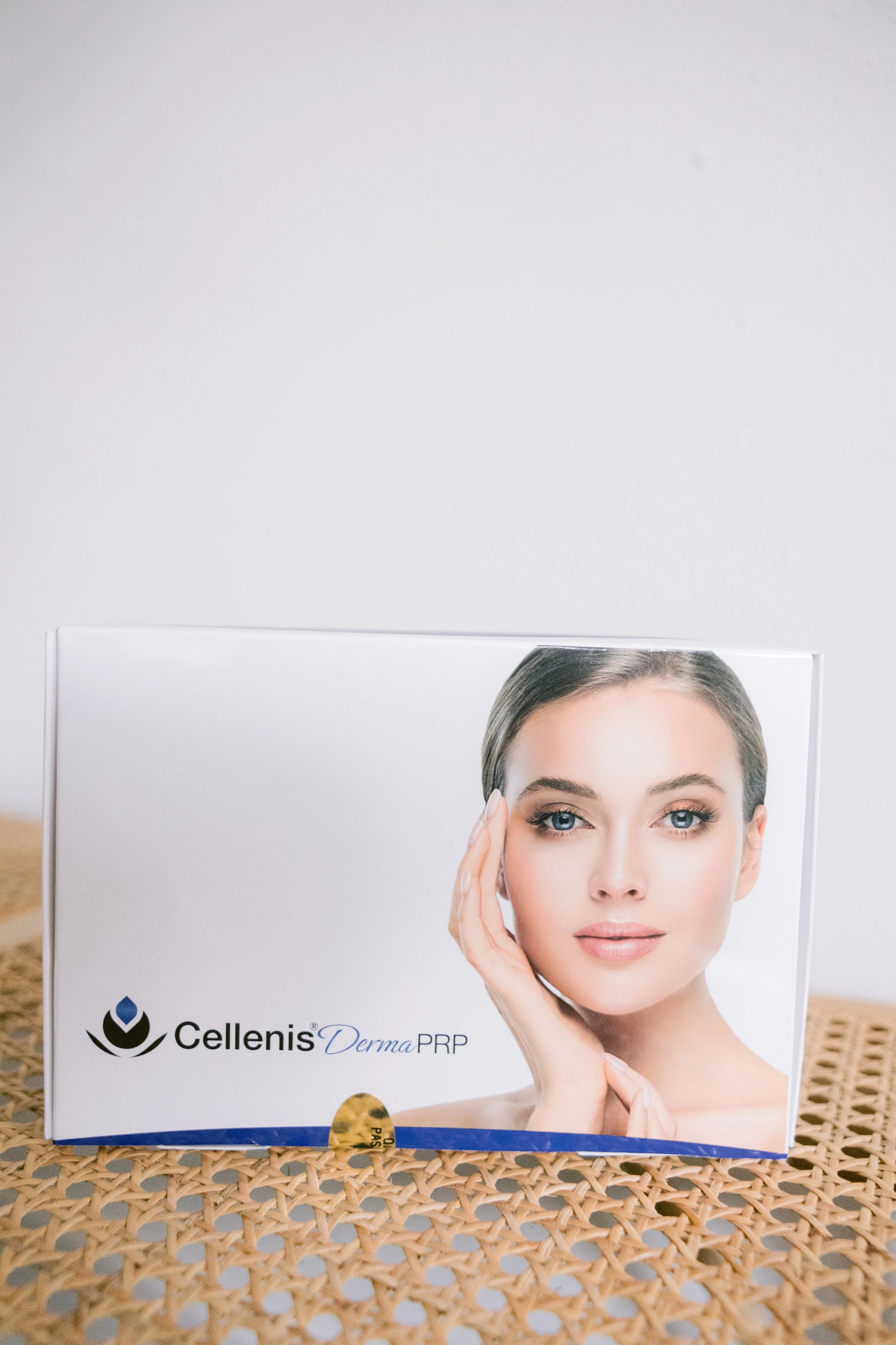Person holding a beige sheet mask in front of a gray background.