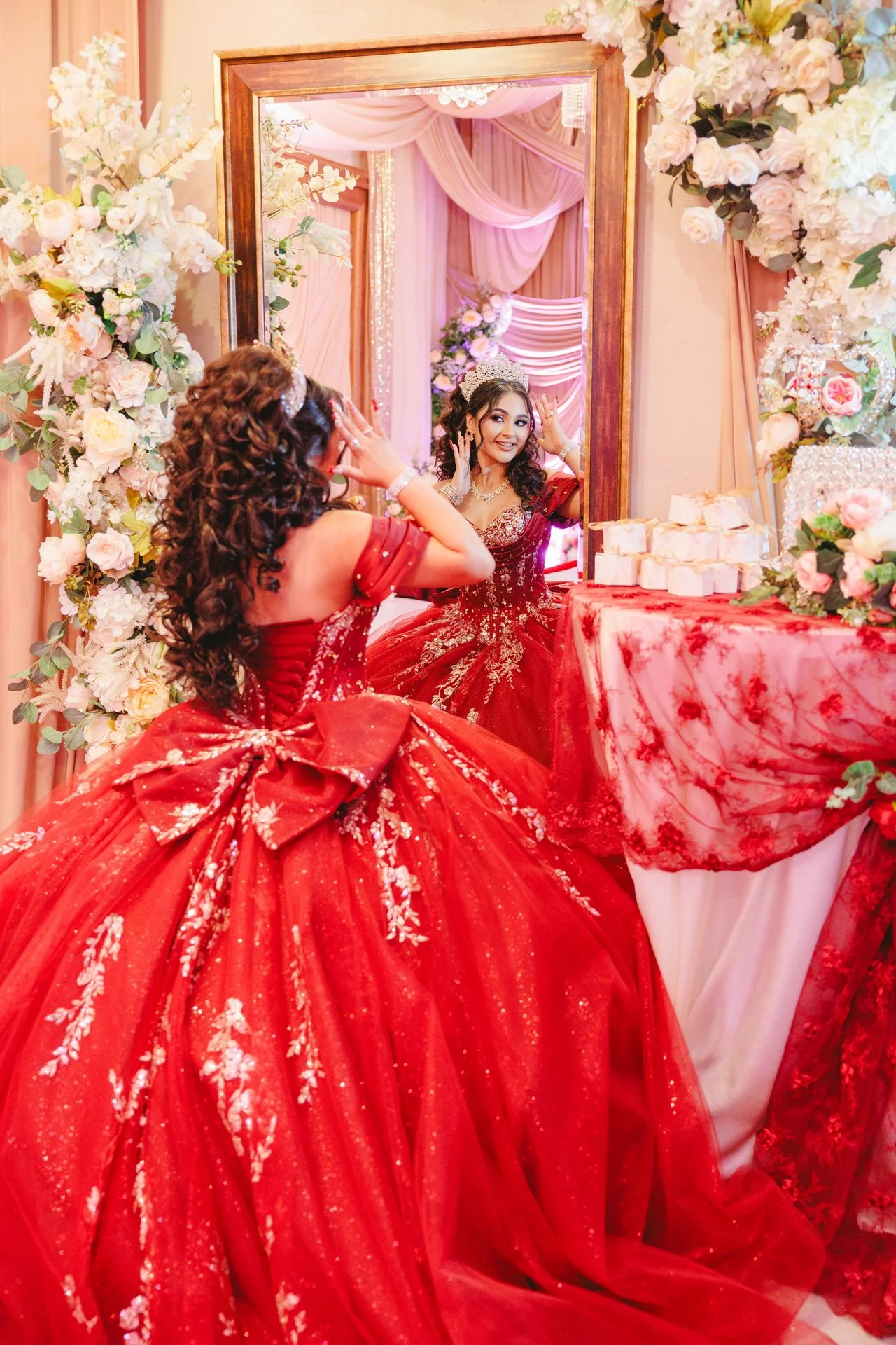 Girl celebrating Quinceneara in elegant red gown, posing in front of mirror