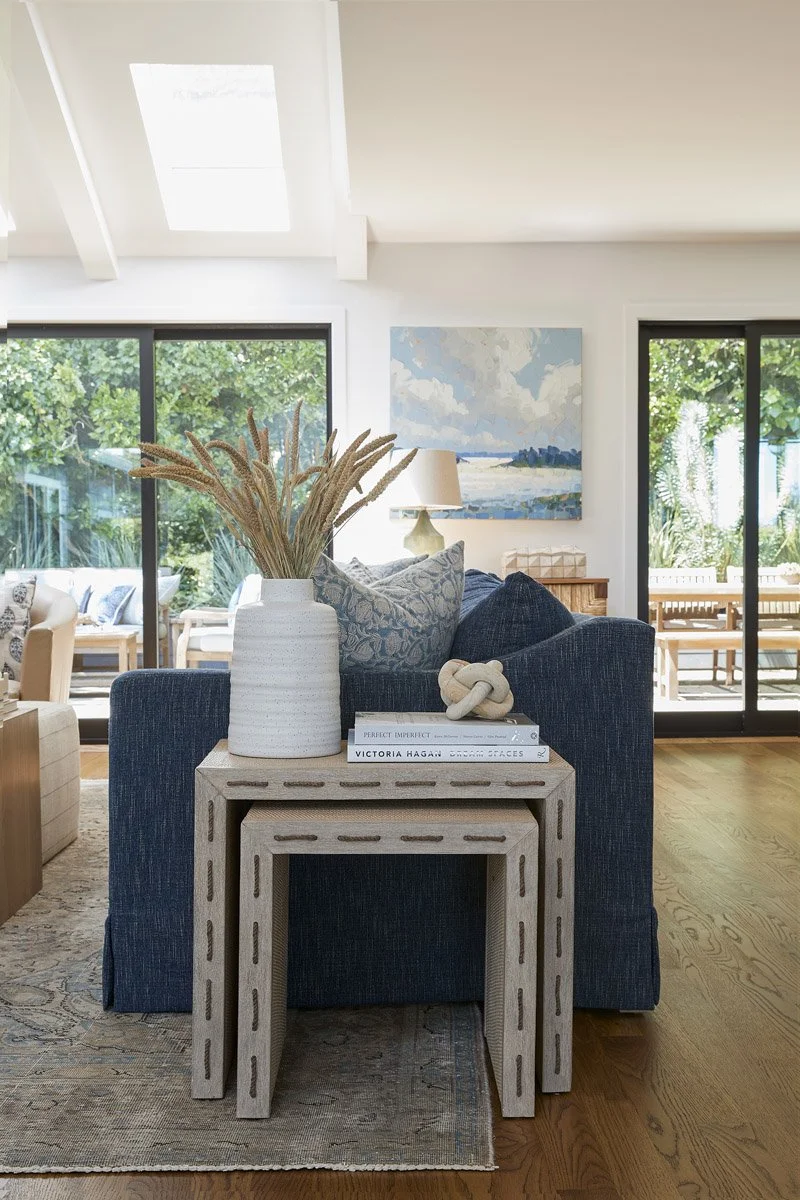 navy sofa with nesting side tables and a vase of dried grasses