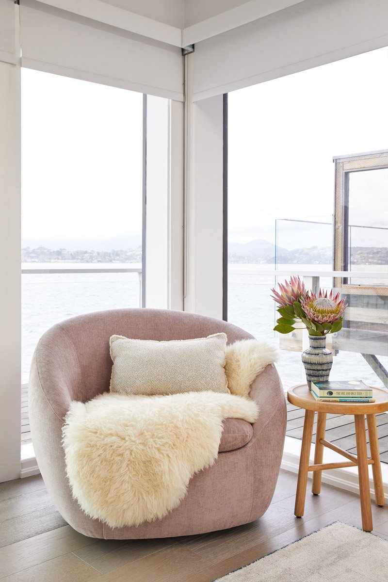 pink swivel chair with sheepskin throw beside a corner window