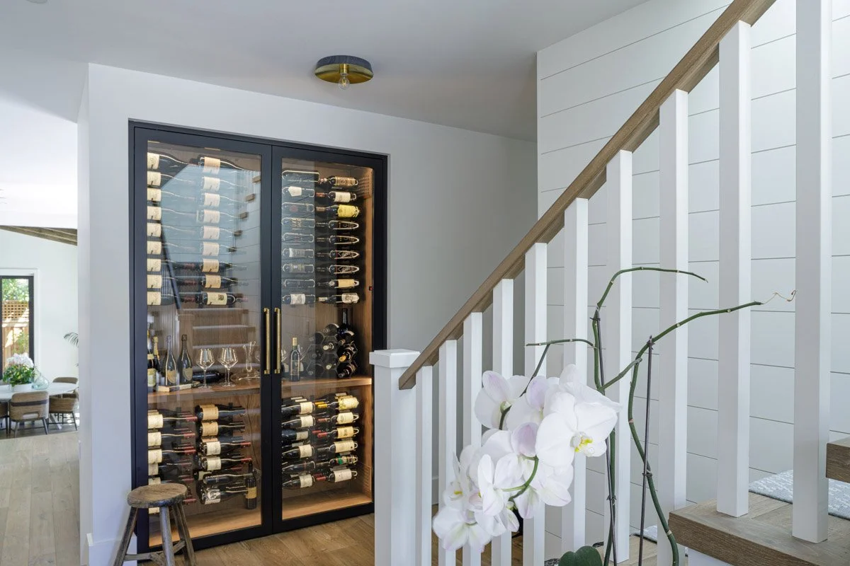 glass-front wine room beneath a white staircase