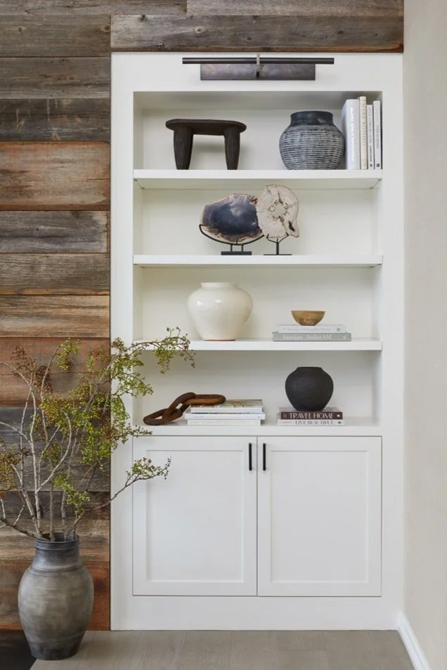 white built-in shelving beside a reclaimed wood wall