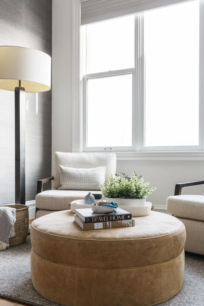 sitting area with cognac leather ottoman and linen floor lamp