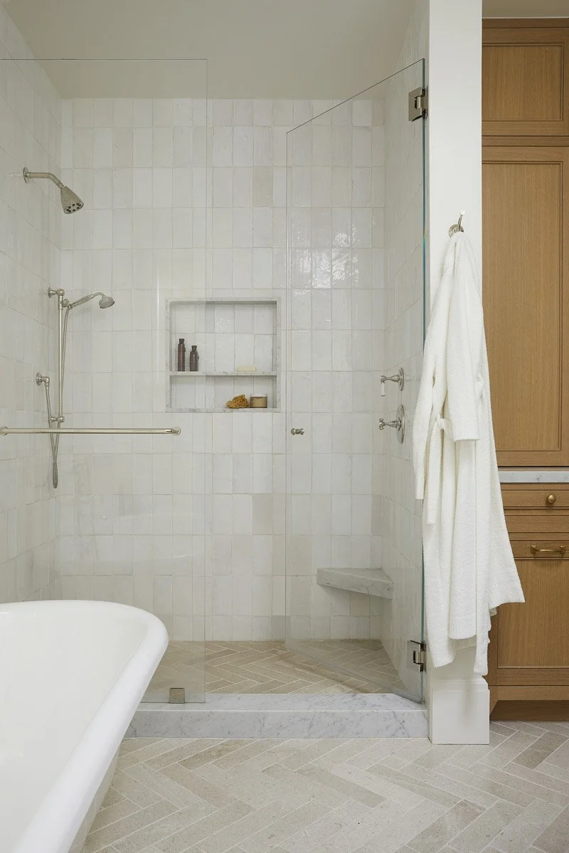 walk-in shower with white tile and built-in niche beside a freestanding tub
