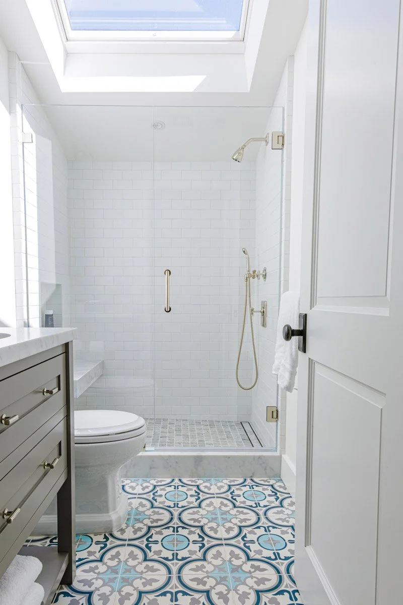 bathroom with blue patterned floor tile, grey vanity and skylight