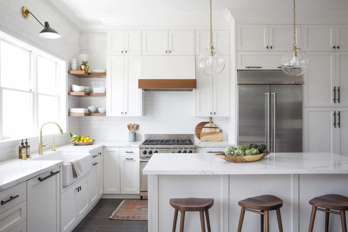 white kitchen with farmhouse sink, stainless appliances and wood counter stools