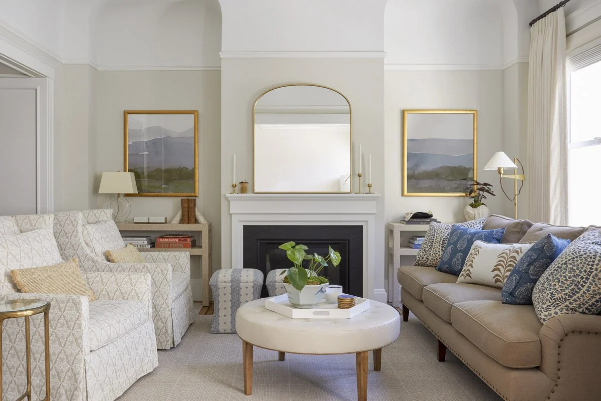living room with fireplace, cream armchairs, blush sofa and round ottoman