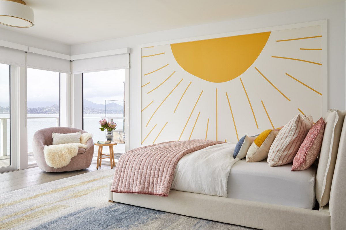 kids bedroom with sunburst wall mural, pink armchair and water views