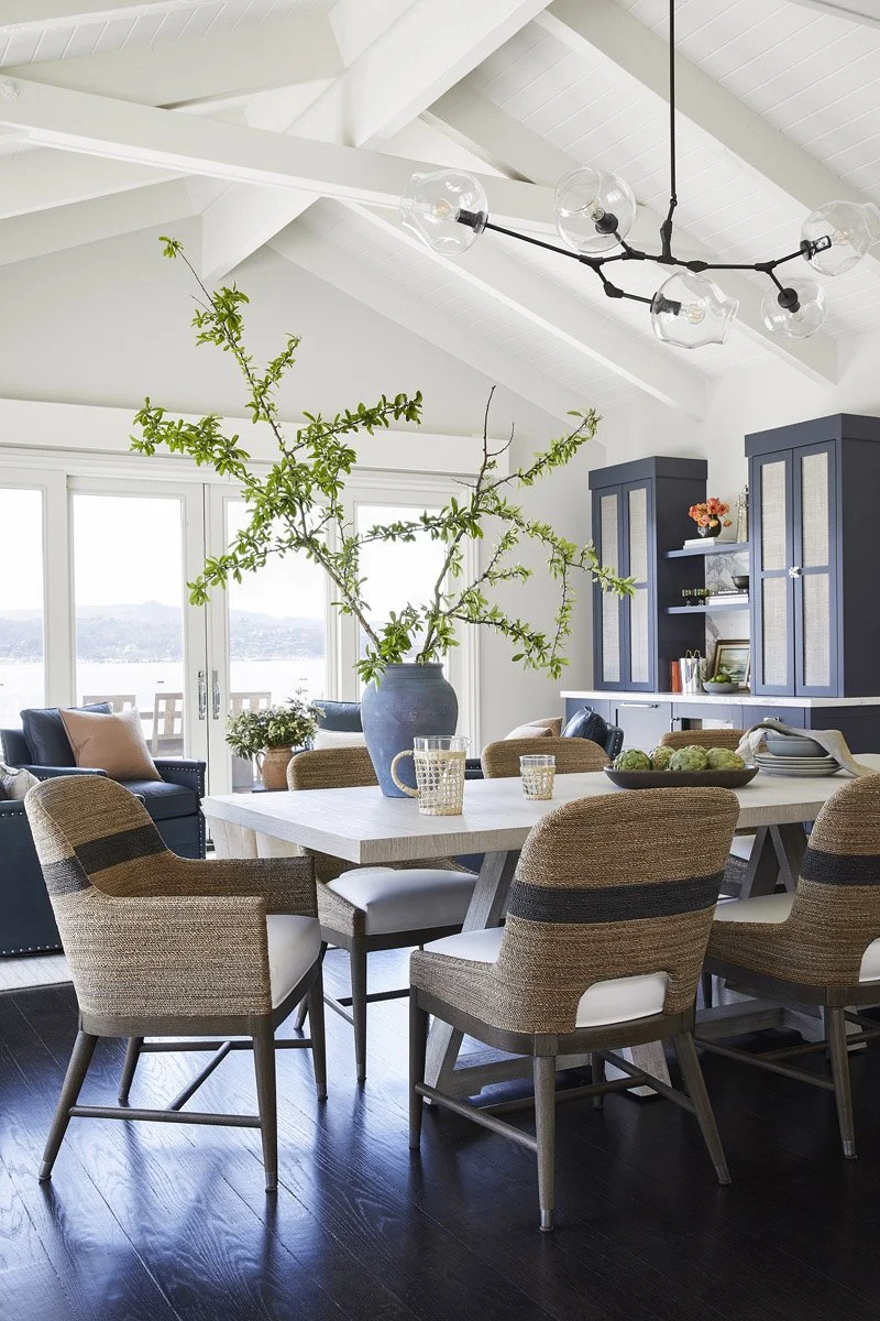 dining room with woven upholstered chairs under a modern black chandelier