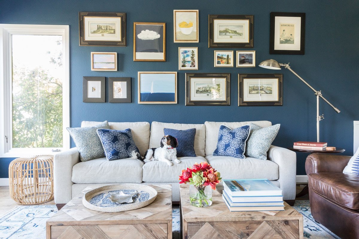 family room with navy walls, gallery wall, white sofa and leather armchair