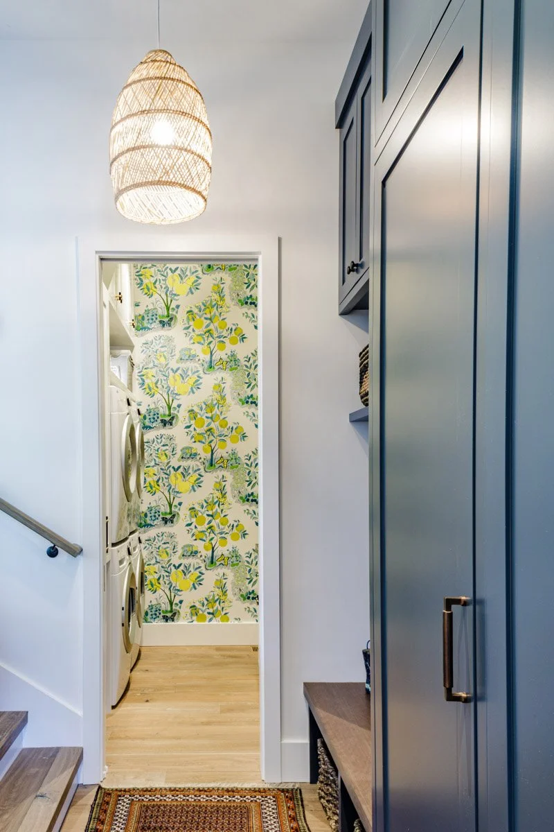 hallway with blue cabinetry leading to a wallpapered laundry room