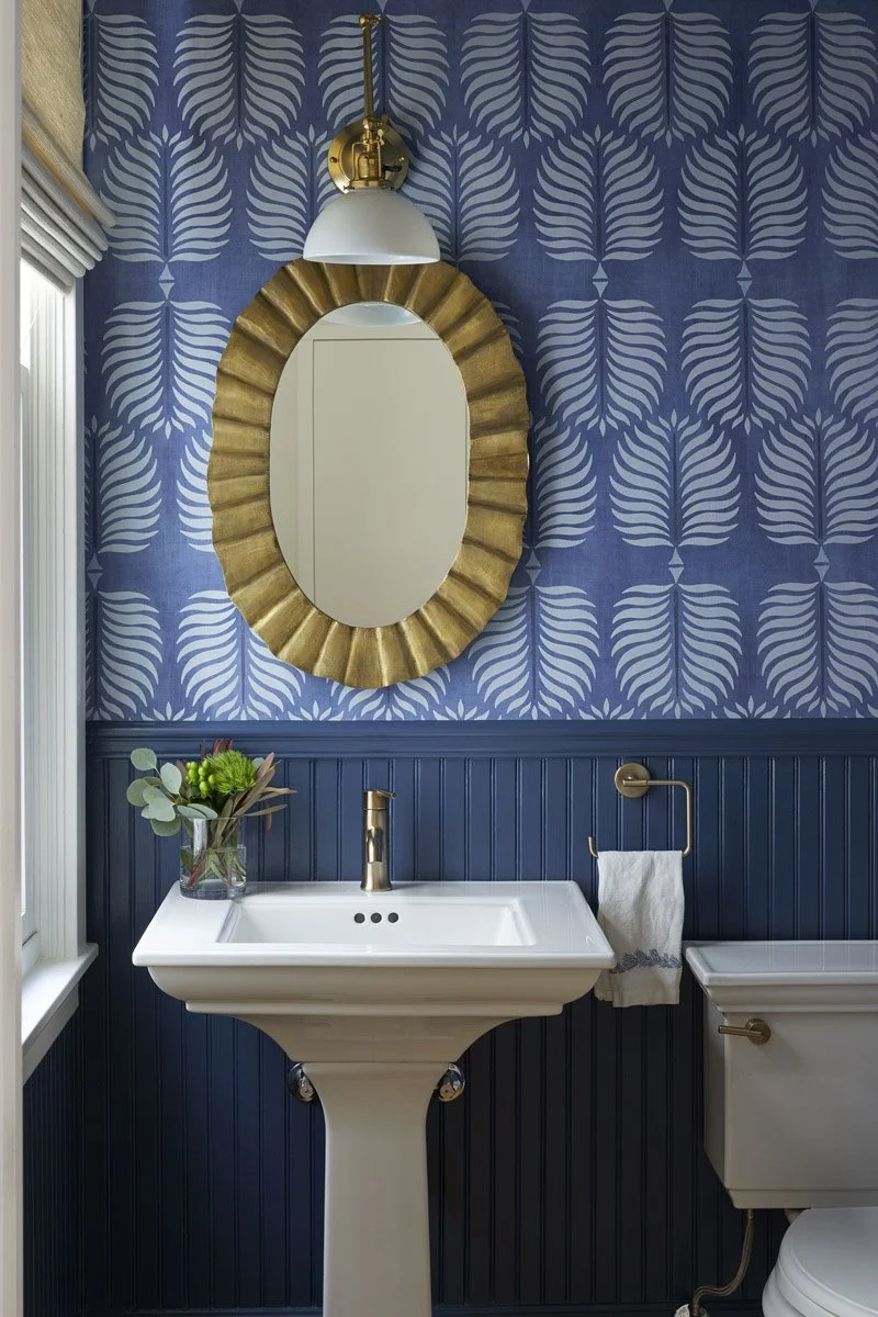 powder room with blue leaf wallpaper, gold oval mirror and pedestal sink