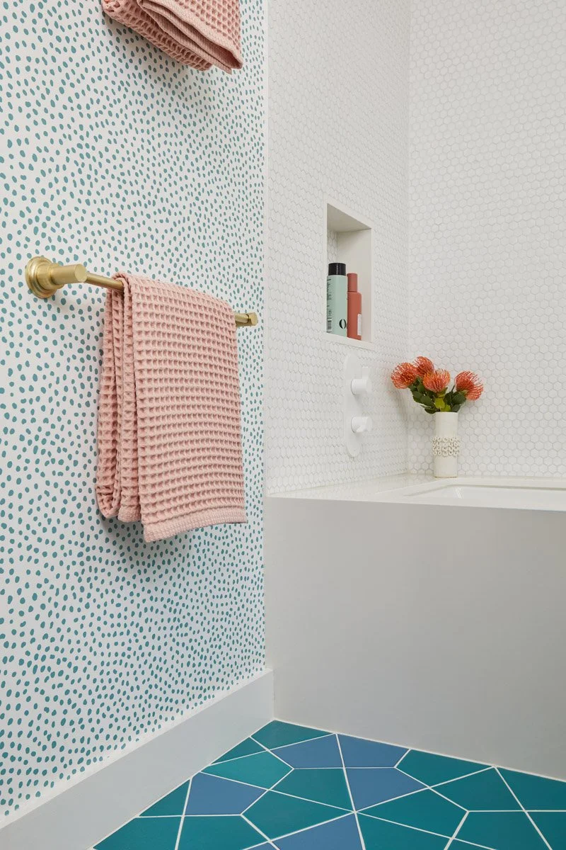 bathroom with speckled wallpaper, teal geometric floor tile and pink towel