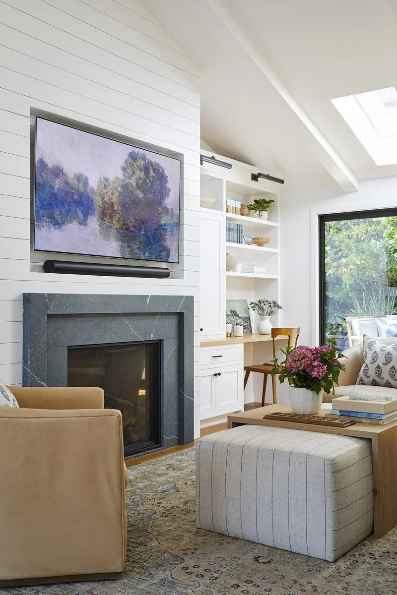 living room with fireplace, framed art TV, swivel chairs and striped ottoman