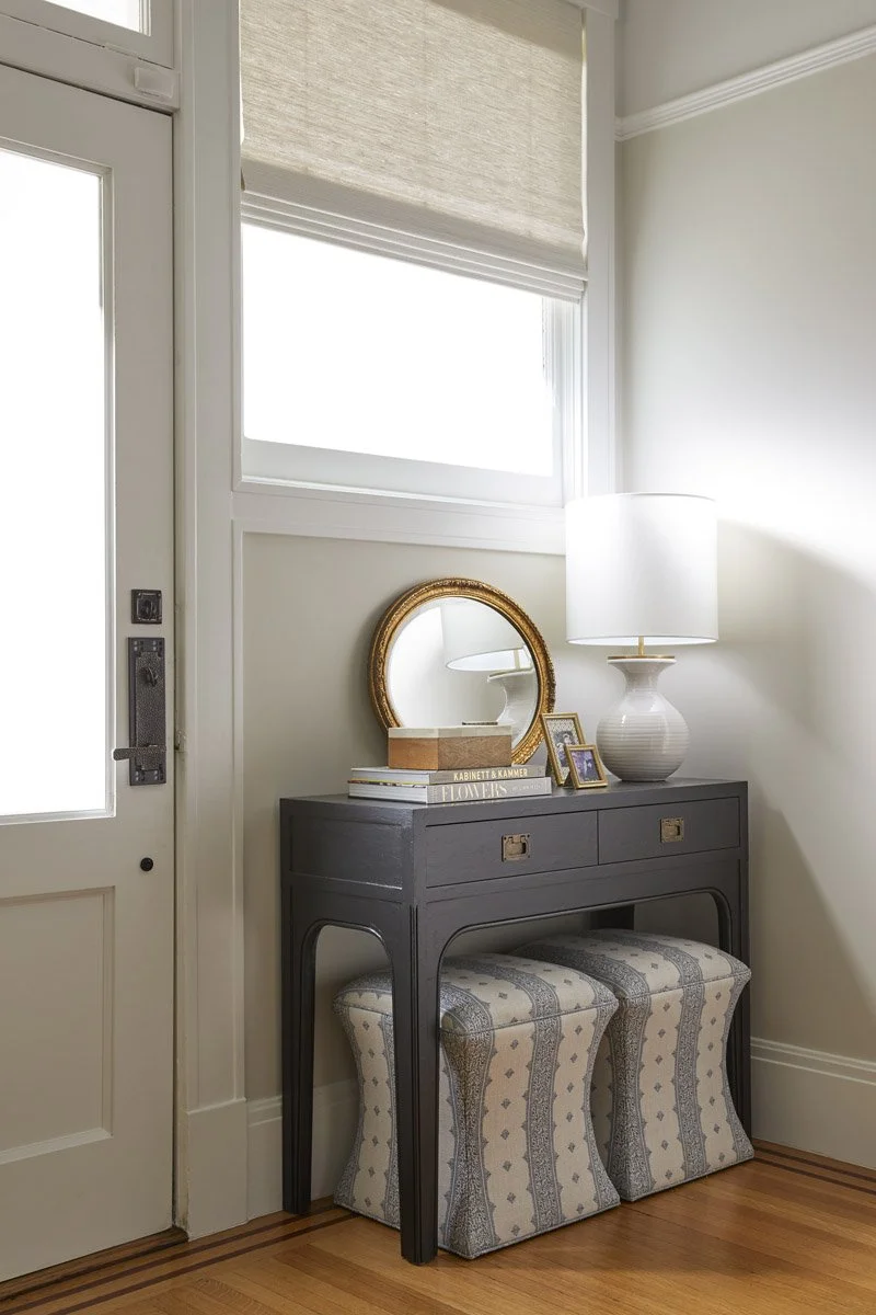 front entry with console table, round mirror and striped stools