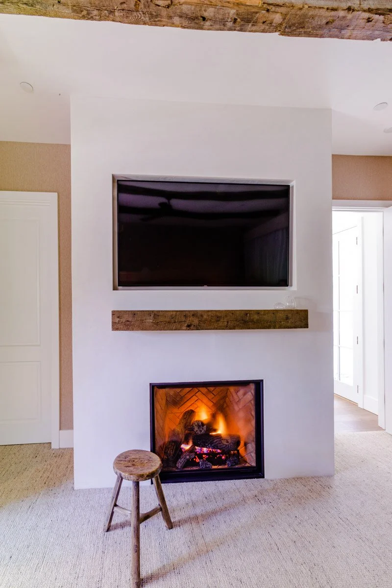 primary bedroom fireplace with wall-mounted TV and reclaimed wood mantel