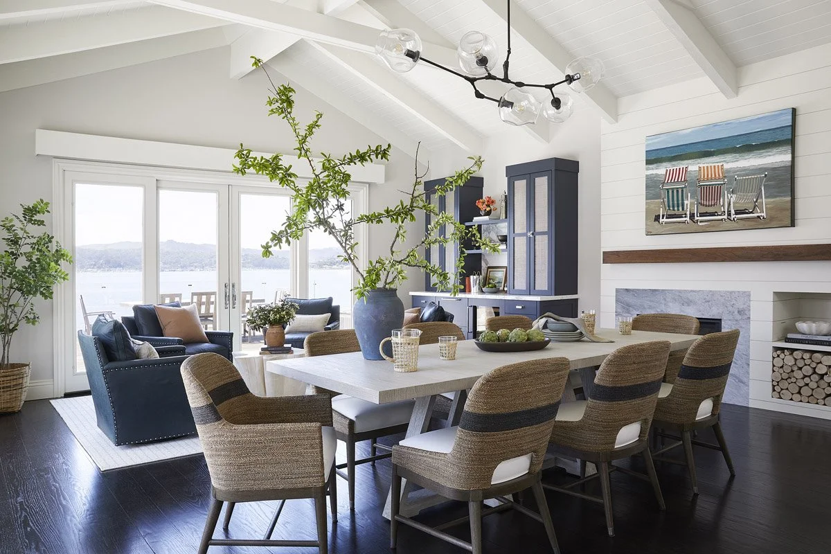 dining table with woven chairs beside a navy seating area and bay views