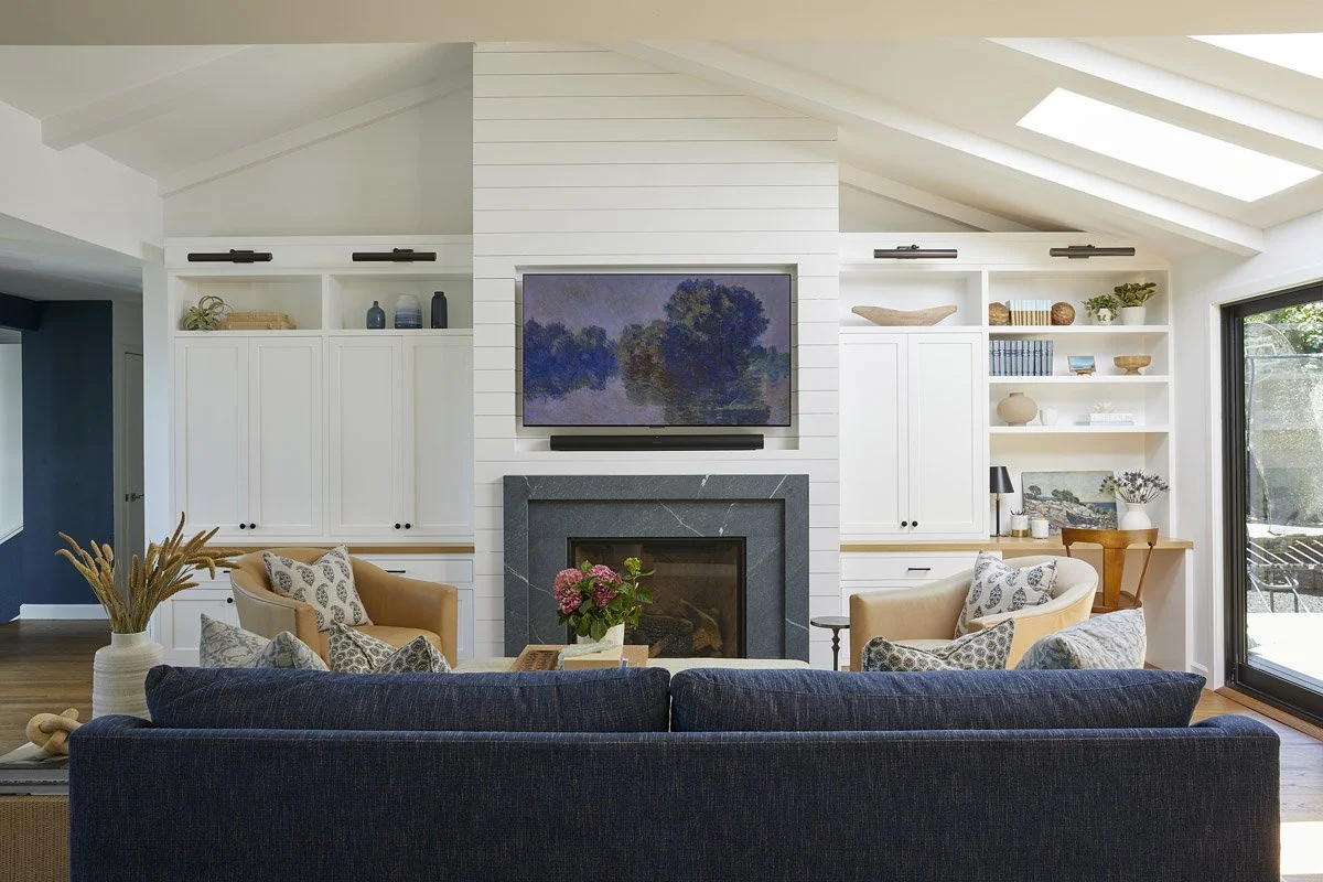 living room with navy sofa facing a fireplace and white built-in shelving