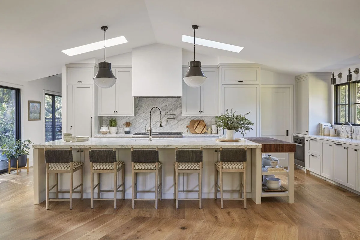kitchen with large island, woven counter stools and vaulted ceiling with skylights