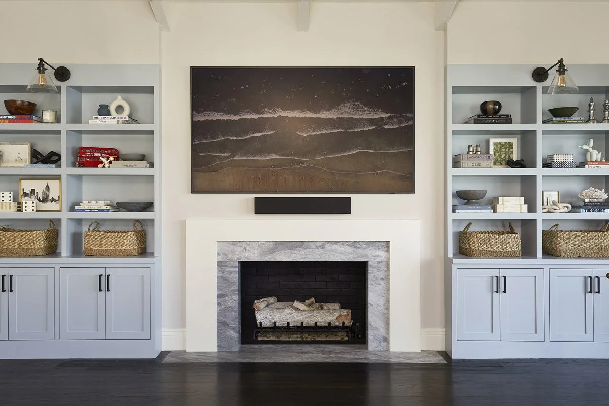 game room with marble fireplace flanked by pale blue built-in shelving