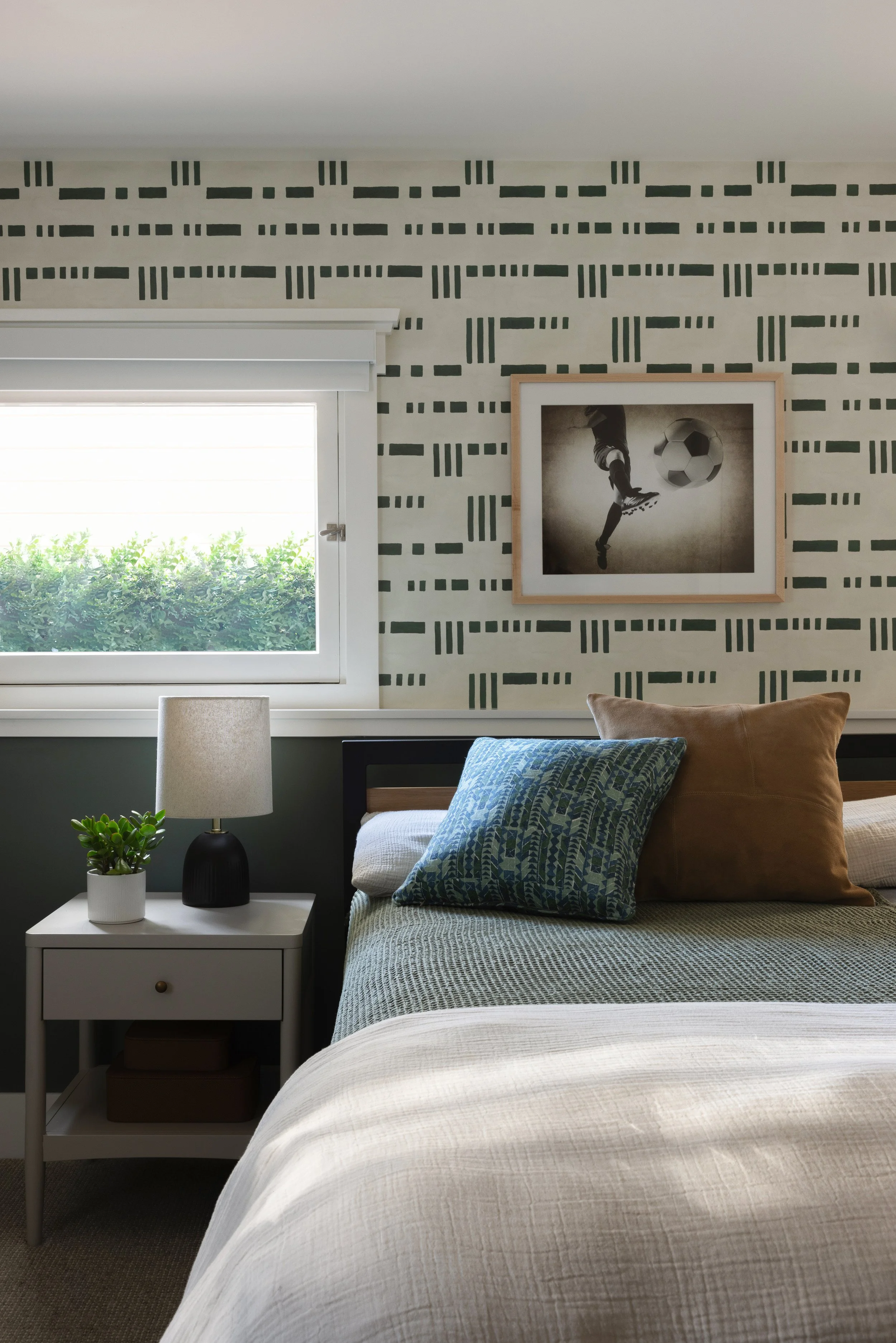 bedroom with patterned wallpaper, framed photograph and blue pillows