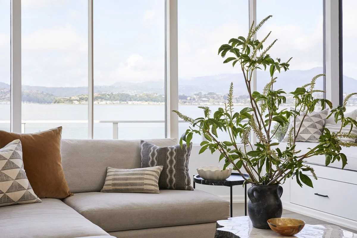 sectional sofa with patterned pillows beside a large window overlooking the bay