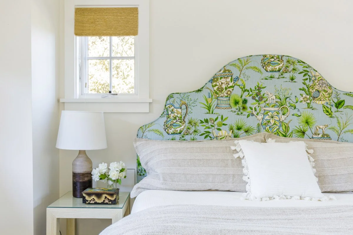 bedroom with green botanical upholstered headboard and white bedding