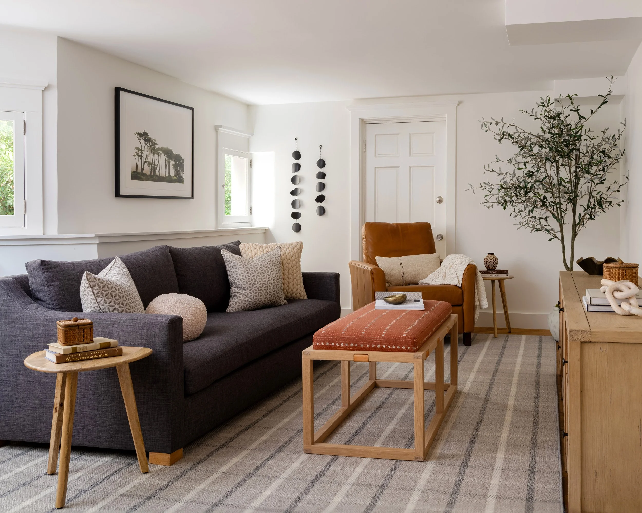 family room with charcoal sofa, rust upholstered bench and plaid rug
